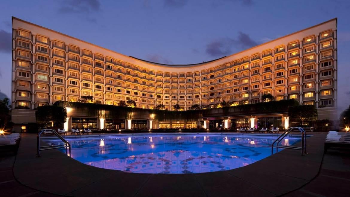Luxury exterior view of The Grand New Delhi featuring illuminated architecture and swimming pool at night